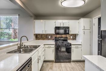 Madison at Black Mountain apartments in Henderson, NV 89015 photo of a kitchen with white cabinets and a black stove top oven